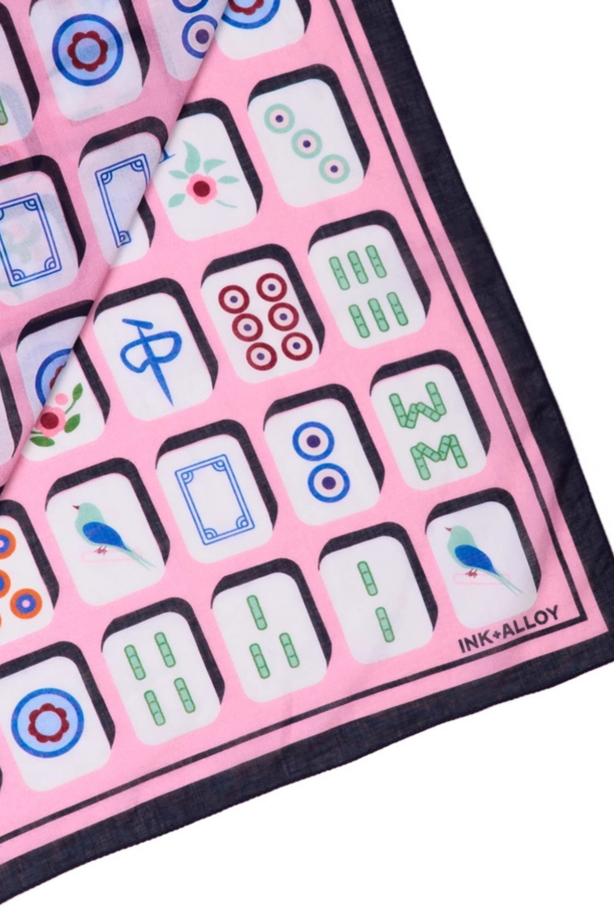 A close-up of a pink silk scarf featuring a traditional Chinese mahjong tile pattern with black borders and the INK+ALLOY brand name printed in the bottom right corner.