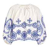 White blouse with blue floral embroidery on a white background