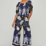 Woman wearing a navy floral jumpsuit on a white background