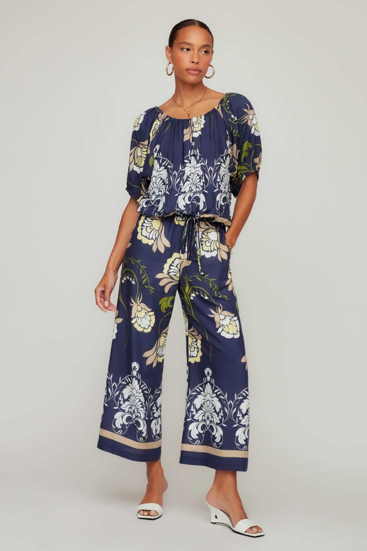 Woman wearing a navy floral jumpsuit on a white background