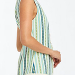 Woman wearing a sleeveless, patterned dress with a white background