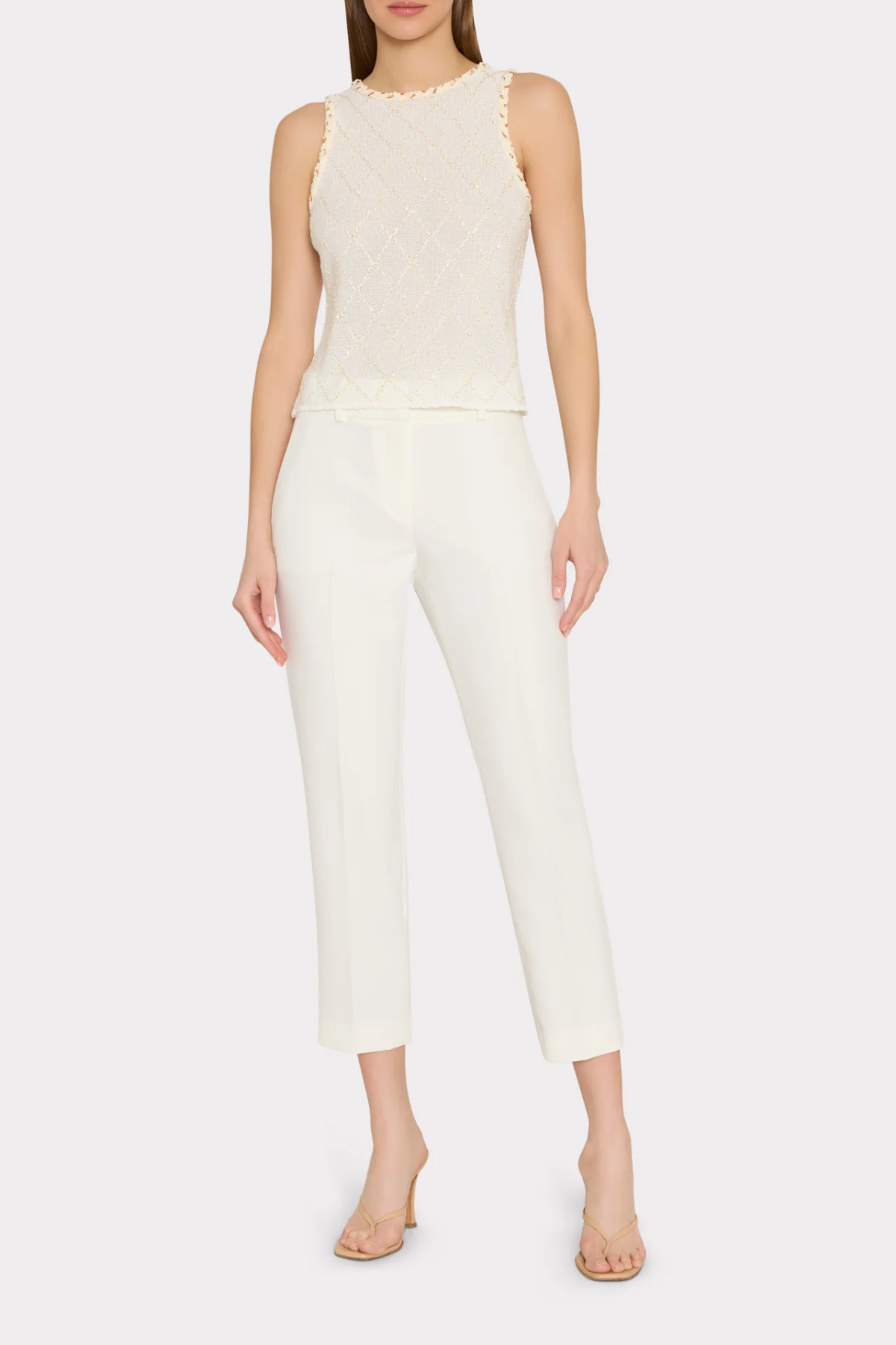Woman wearing a white sleeveless top and pants on a white background