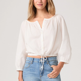 Woman wearing a white blouse and blue jeans on a plain background