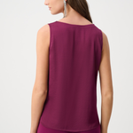 Woman wearing a sleeveless purple top and pants on a white background