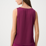Woman wearing a sleeveless purple top and pants on a white background