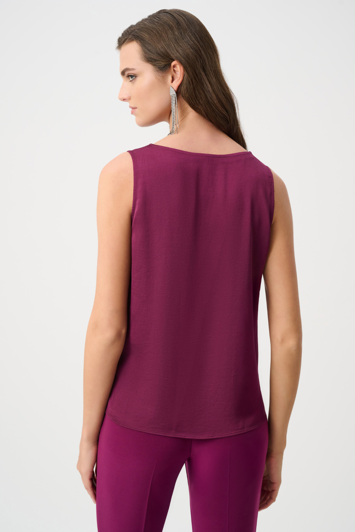 Woman wearing a sleeveless purple top and pants on a white background