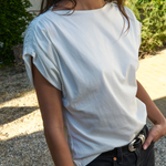 Person wearing a light blue t-shirt and black pants outdoors.