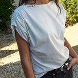 Person wearing a light blue t-shirt and black pants outdoors.