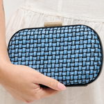 Blue woven clutch held by a person against a neutral background