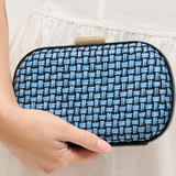 Blue woven clutch held by a person against a neutral background