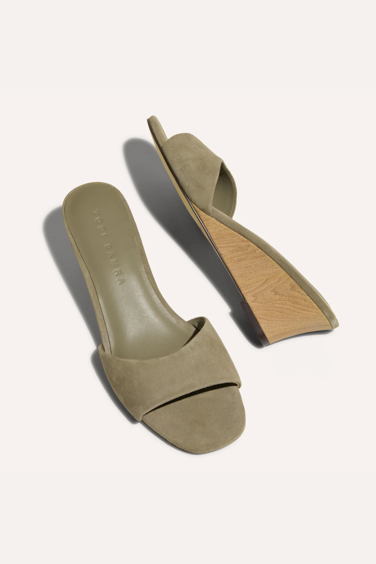 Pair of green suede sandals on a white background