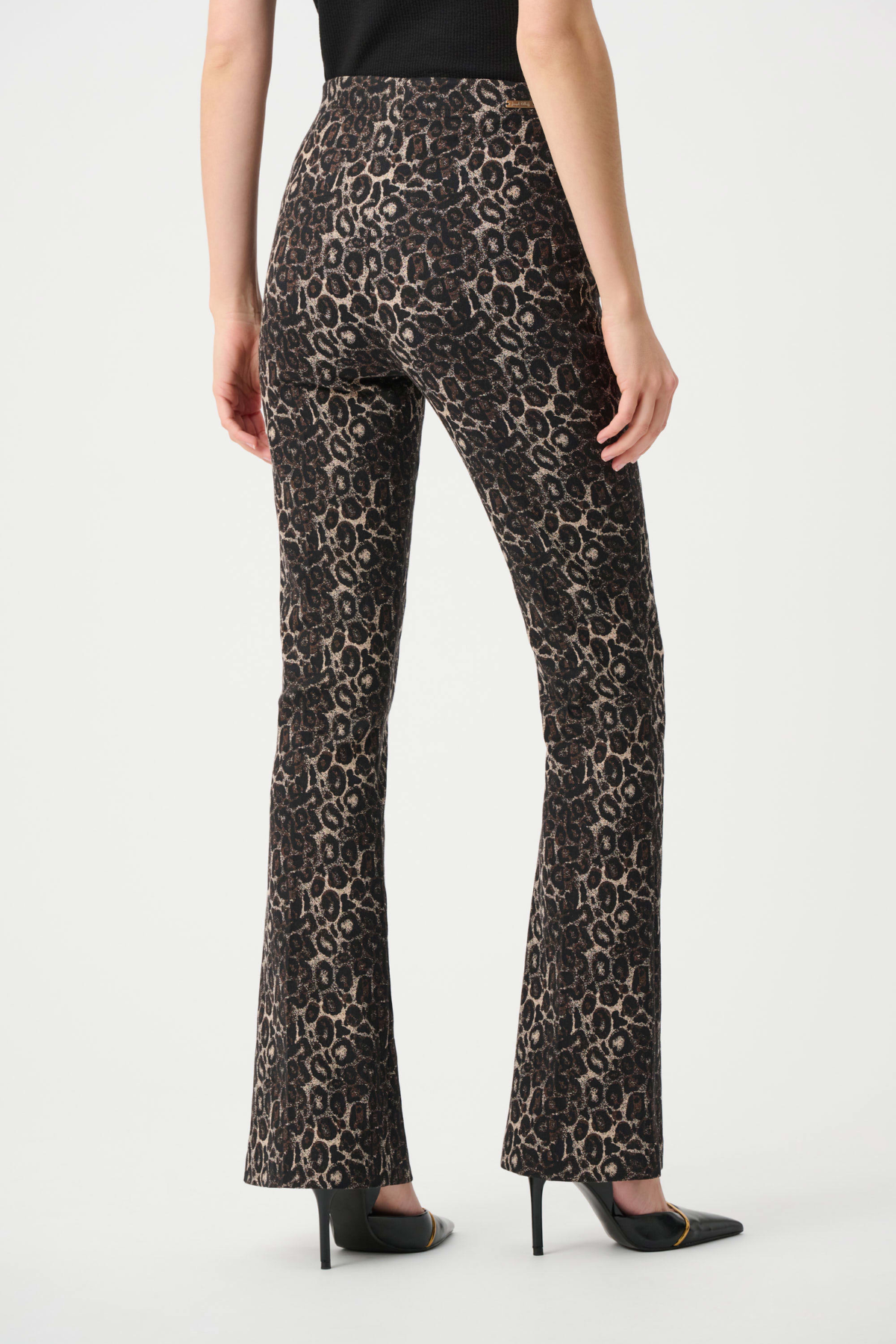 A model shown from the back wearing high-waisted leopard-print flare pants in brown and beige, paired with a black top and black pointed-toe heels.