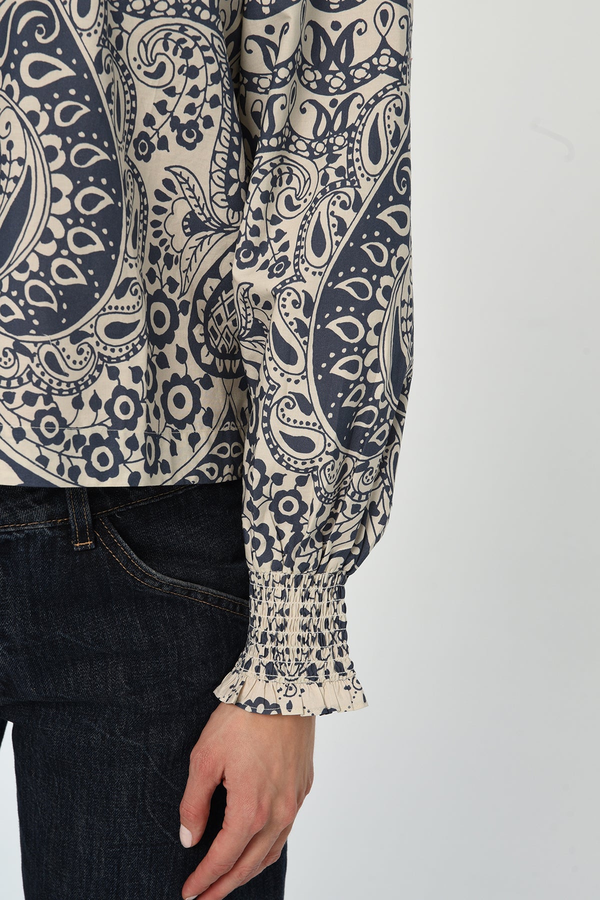 Woman wearing a patterned long sleeve blouse with a gathered neckline in neutral tones