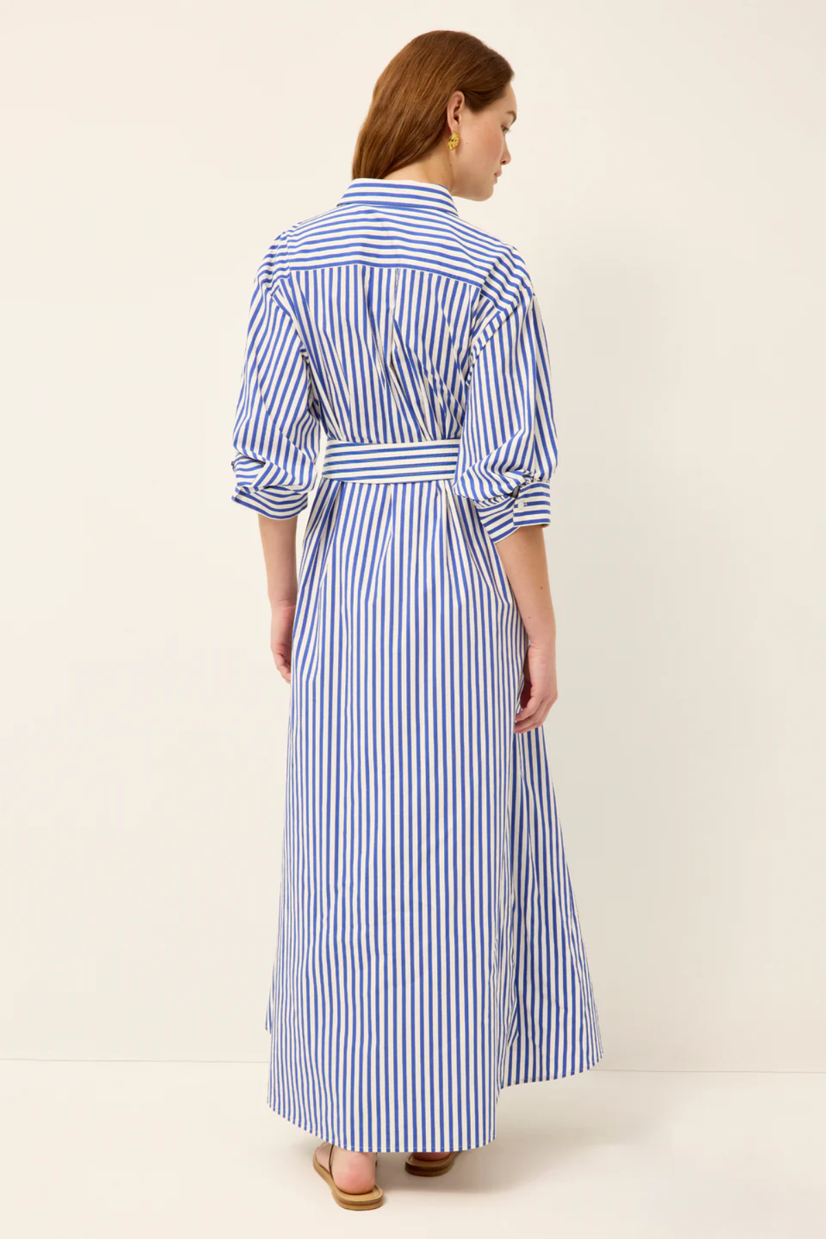 Woman wearing a blue and white striped dress on a plain background