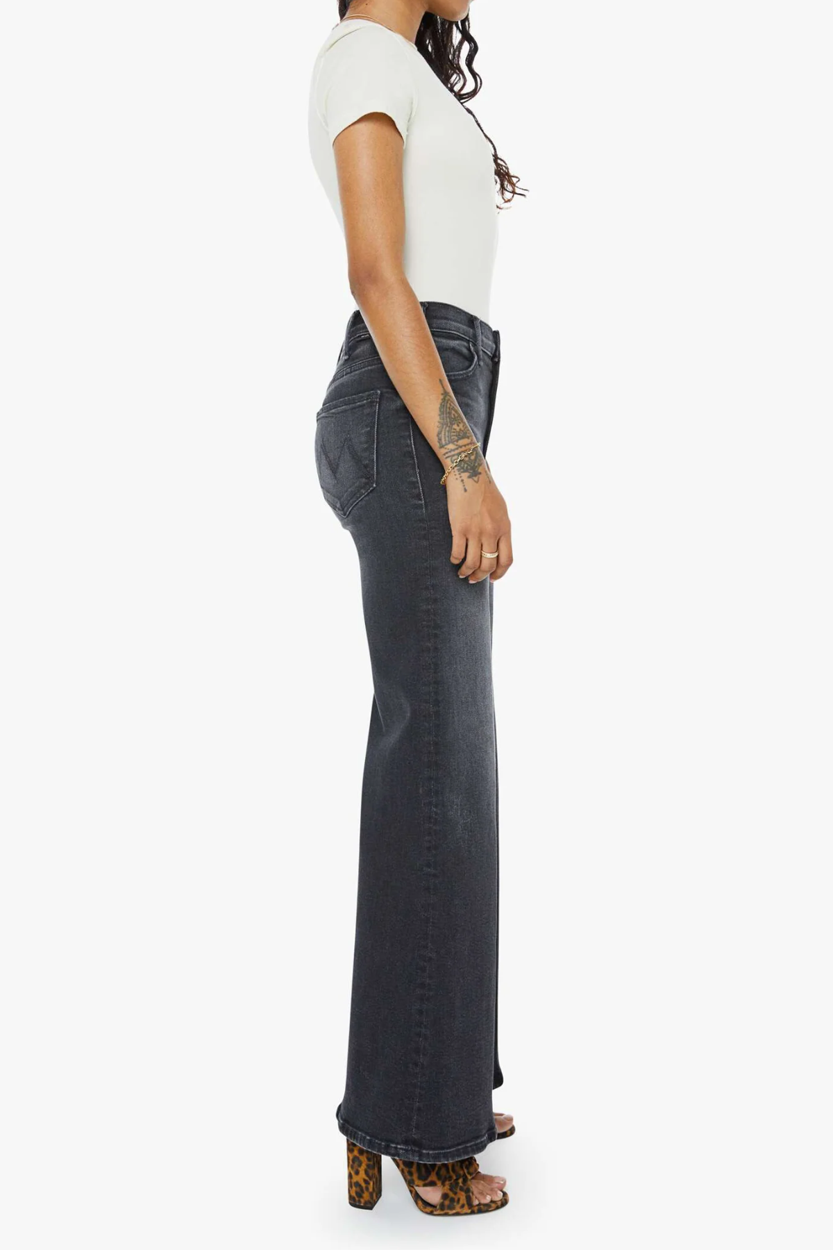 Person wearing dark flared jeans and a white top on a white background