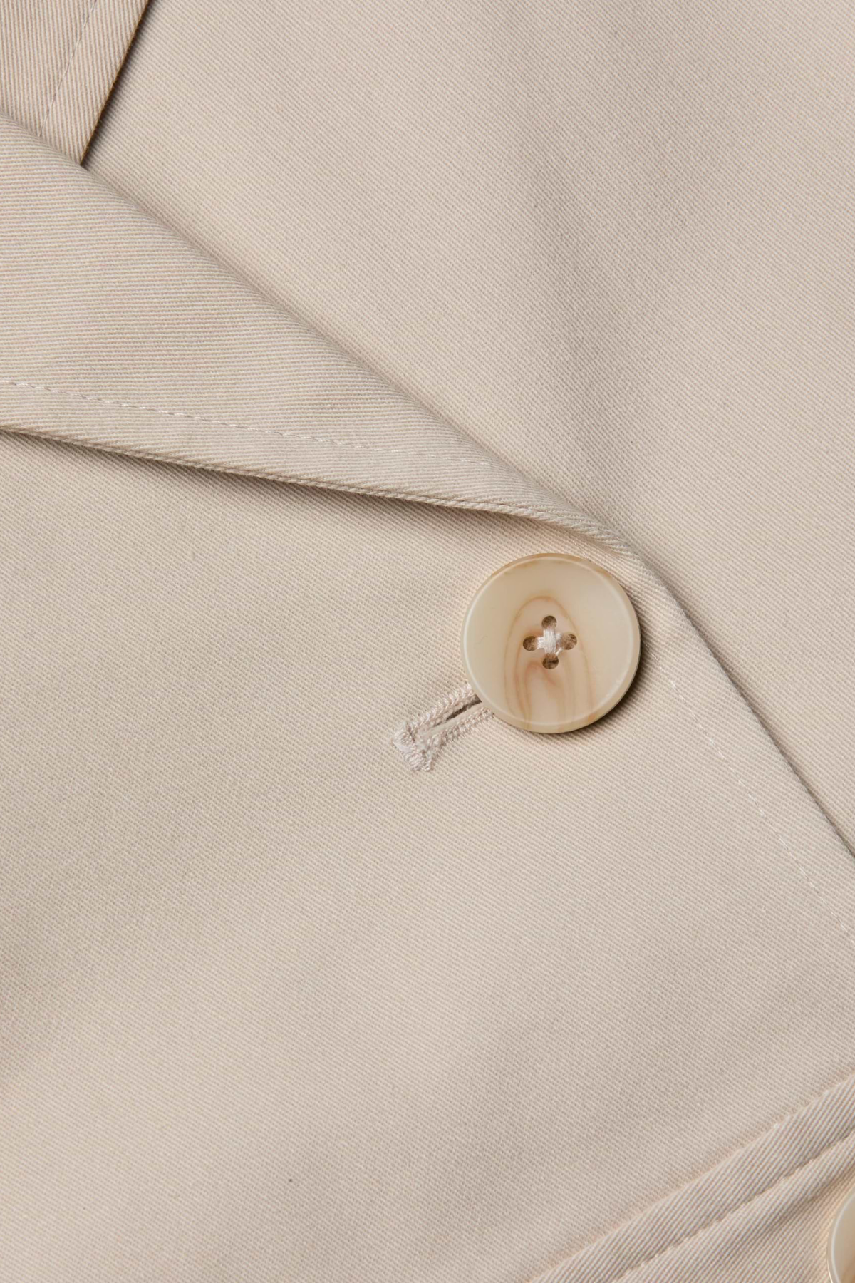 Close-up of a beige fabric with a button on a garment