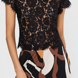 Black lace top worn by a person with a white background