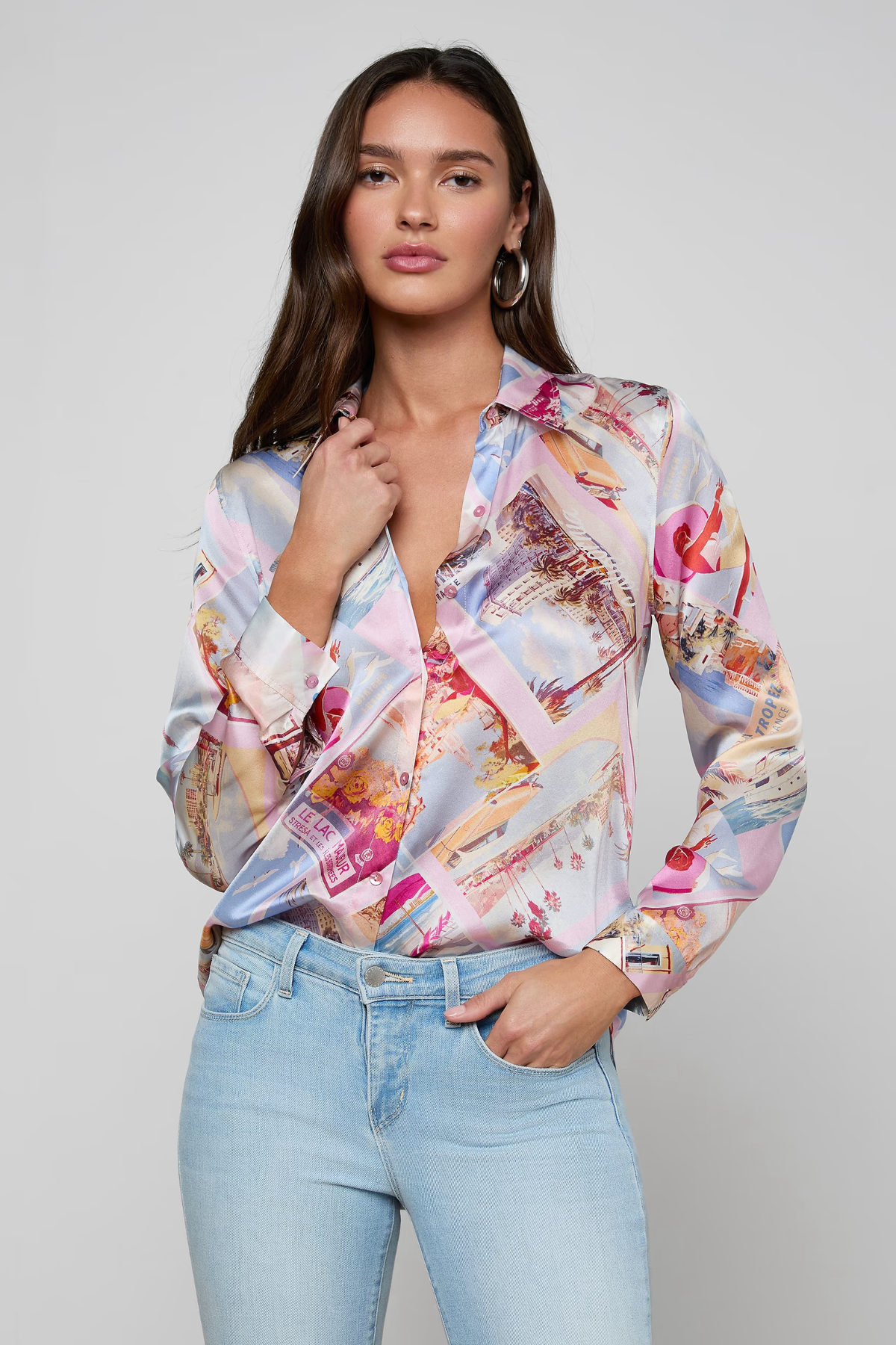 Woman wearing a colorful patterned blouse and light blue jeans on a gray background