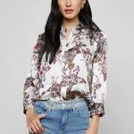 Woman wearing a floral blouse and blue jeans against a gray background