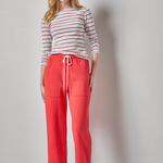 woman in striped tee and red pants on white background 
