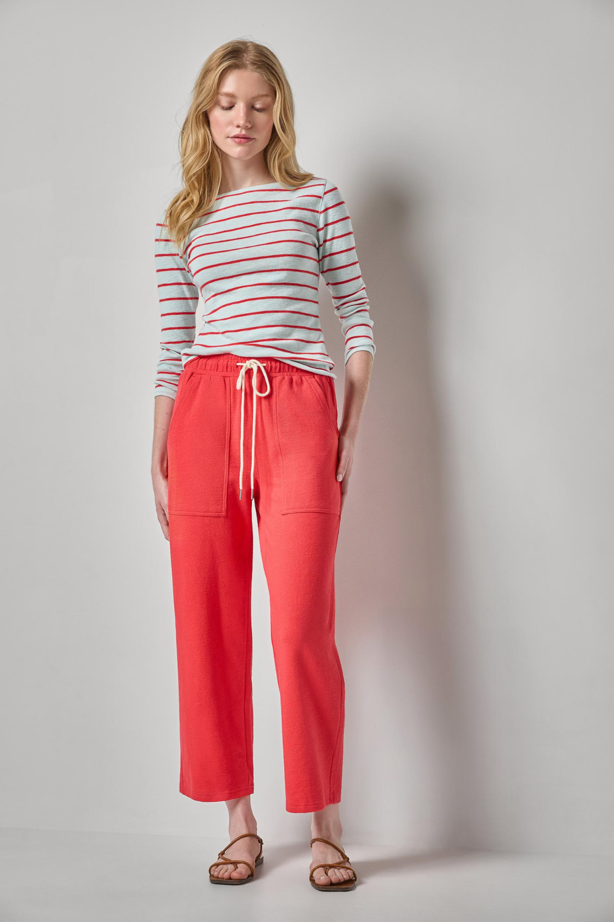 woman in striped tee and red pants on white background 