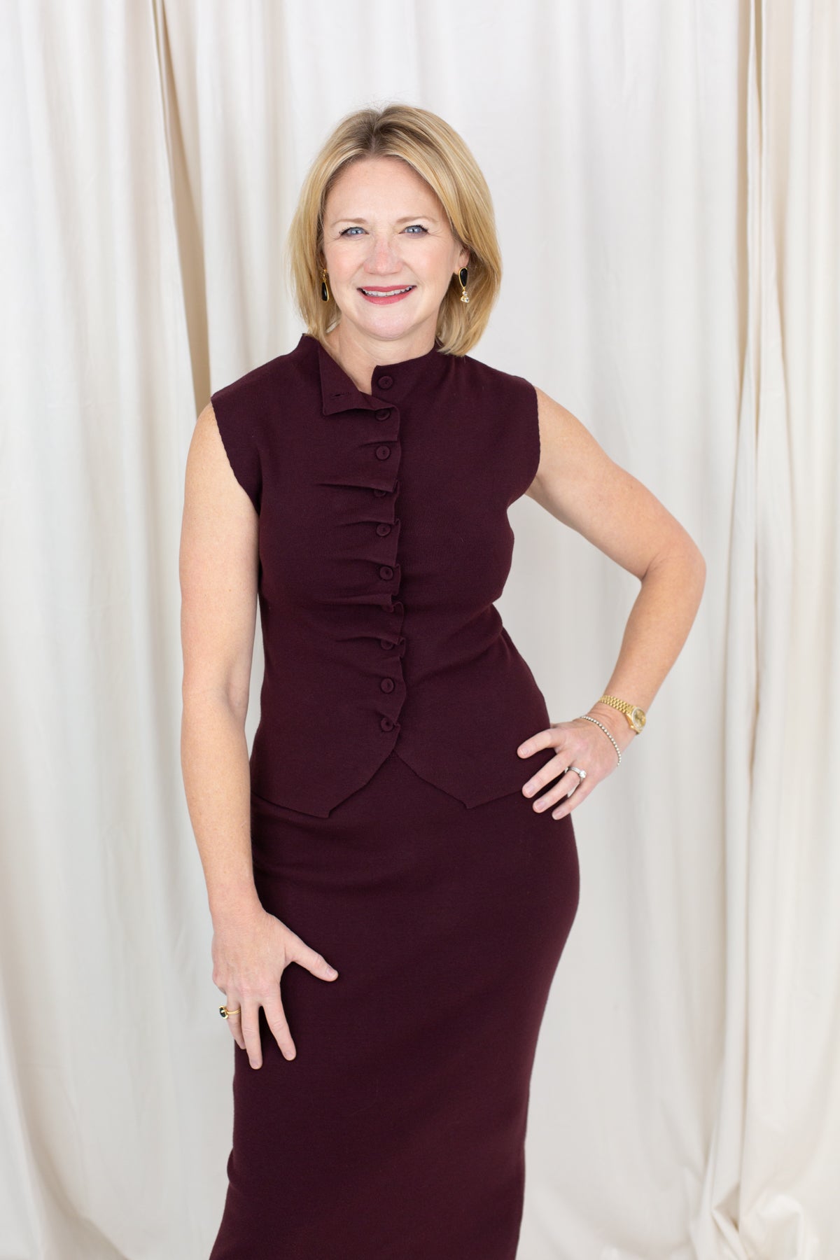 Coordinated burgundy pleated top and skirt set styled for a polished seasonal look