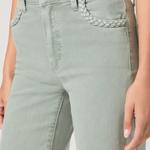 Light green jeans with braided detail on a plain background