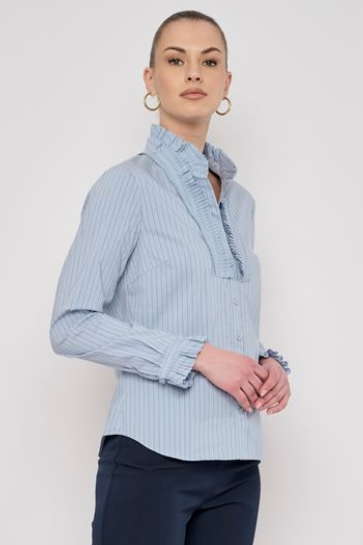 Model wearing a striped long-sleeve blouse with ruffle detailing and a relaxed, polished silhouette.