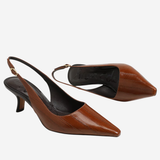 A pair of brown leather slingback pumps with pointed toes and kitten heels, displayed against a light gray background.