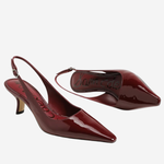 A pair of glossy patent leather slingback pumps in a deep burgundy red, displayed on a clean white background.