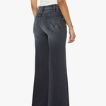 Person wearing dark flared jeans on a white background