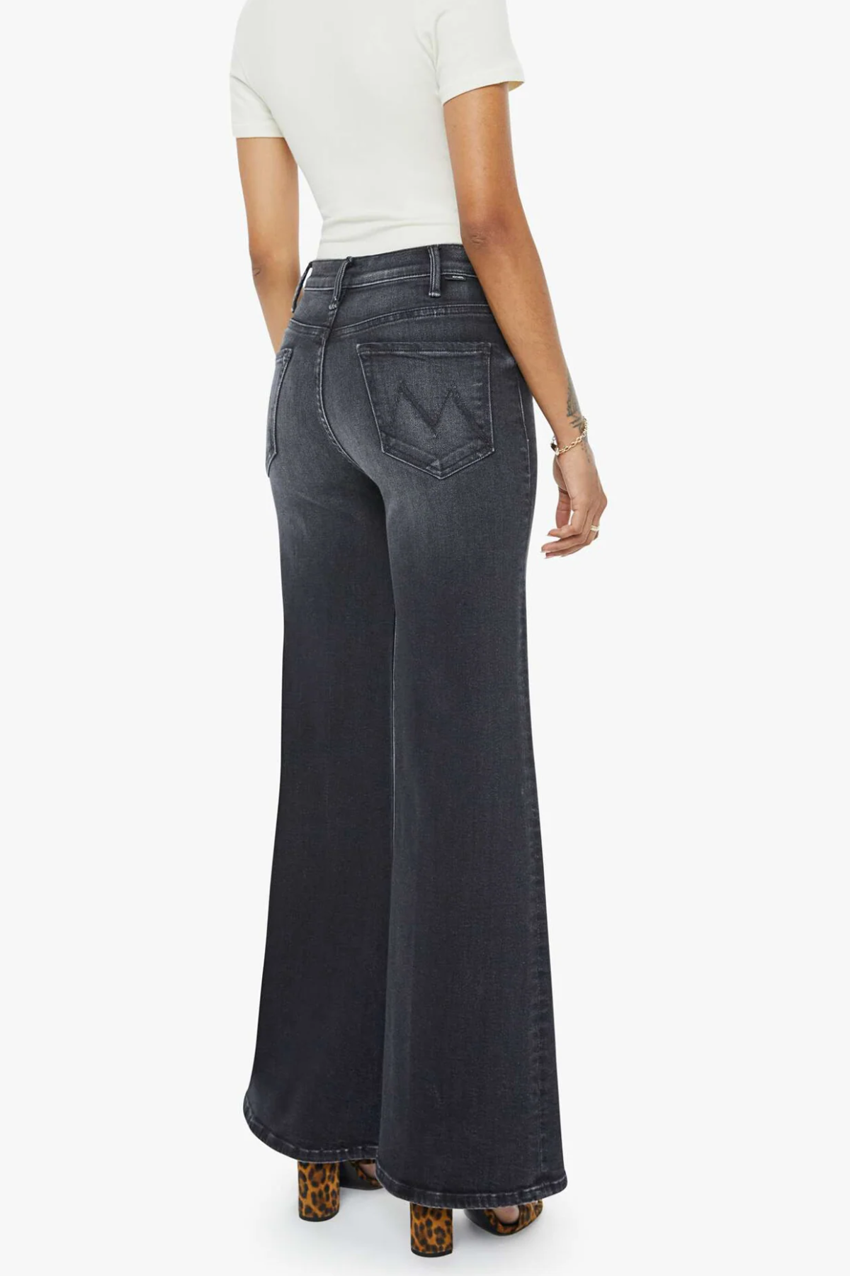 Person wearing dark flared jeans on a white background