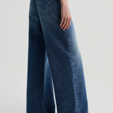 Model wearing high-rise wide-leg denim pants with a relaxed, full-length silhouette.