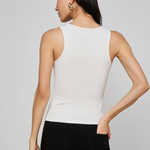 Woman wearing a white sleeveless top and black pants on a gray background