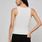 Woman wearing a white sleeveless top and black pants on a gray background