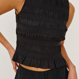 Black smocked top worn by a person on a white background