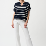 Woman wearing a black and white striped shirt and white pants on a white background