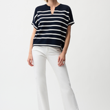 Woman wearing a black and white striped shirt and white pants on a white background