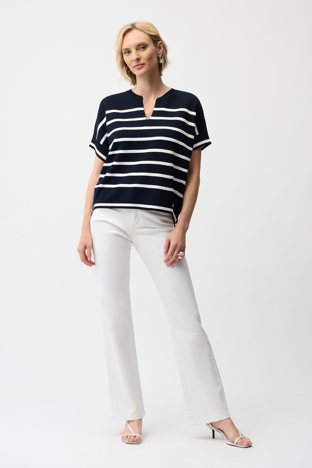 Woman wearing a black and white striped shirt and white pants on a white background