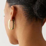 Gold hoop earring worn by a person with a neutral background