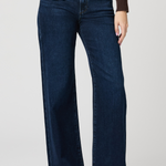 Person wearing dark blue jeans on a plain background