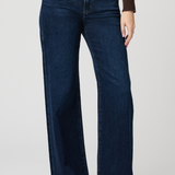 Person wearing dark blue jeans on a plain background