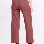 A person shown from the back wearing dusty rose wide-leg cropped pants with black ankle boots against a plain light gray studio background.