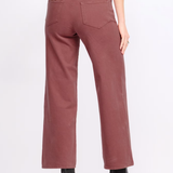 A person shown from the back wearing dusty rose wide-leg cropped pants with black ankle boots against a plain light gray studio background.