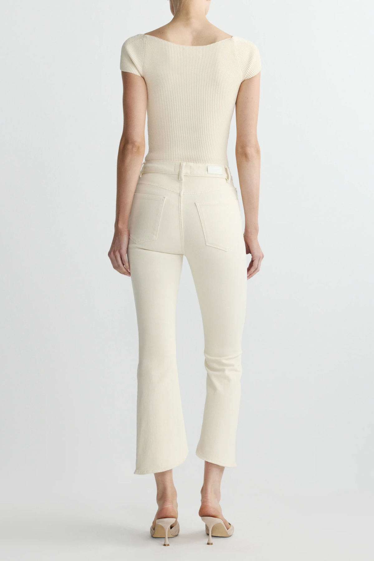 back view of woman in cream outfit on white background 