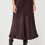 A model wearing a dark brown satin midi skirt with a drawstring waist and dark brown pointed-toe ankle boots, shown from the waist down on a light gray studio background.