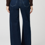 Person wearing dark blue wide-leg jeans on a plain background