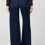 Person wearing dark blue wide-leg jeans on a plain background