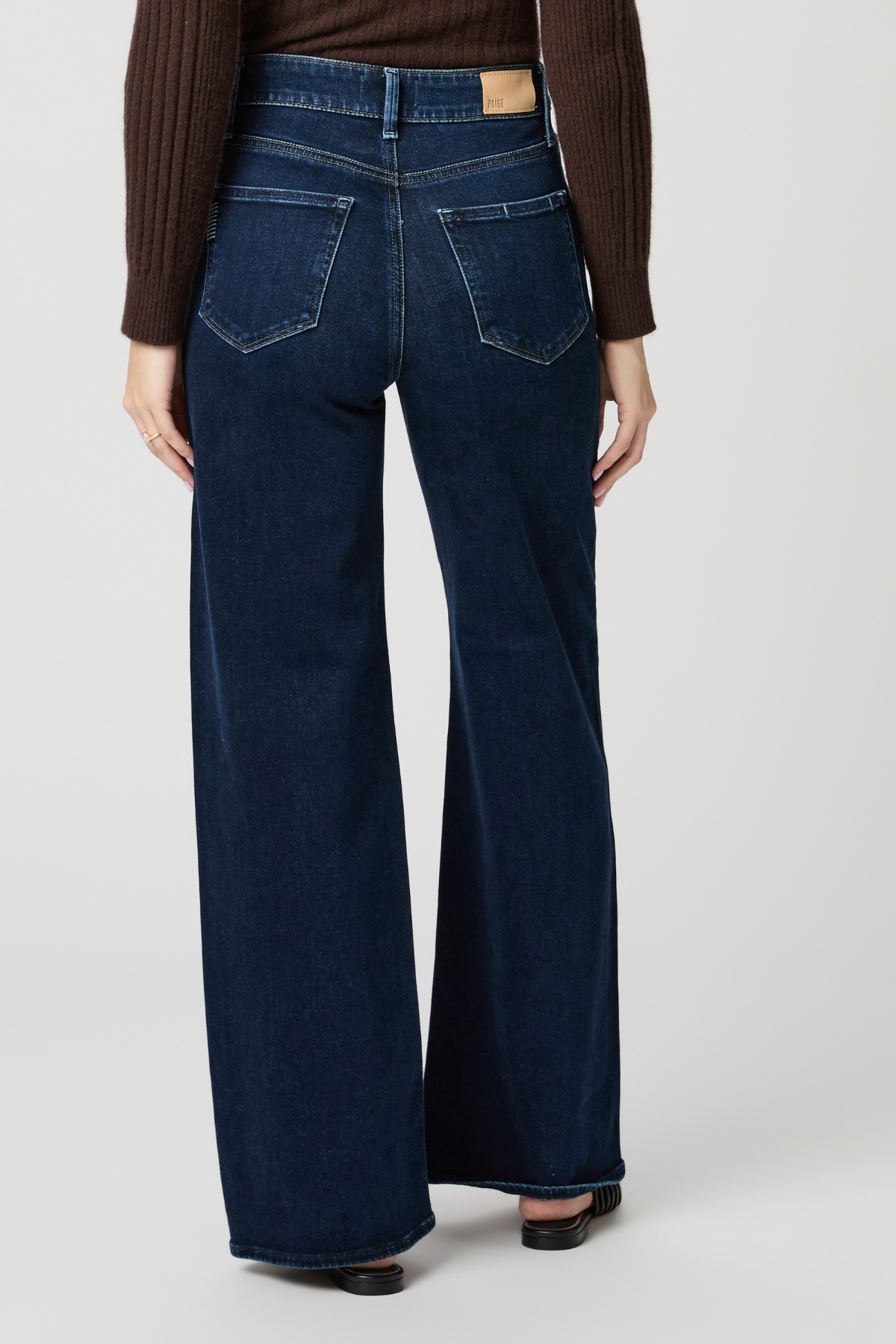 Person wearing dark blue wide-leg jeans on a plain background