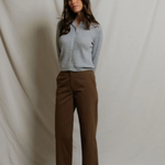 woman in grey cardigan and brown pants on draped background 